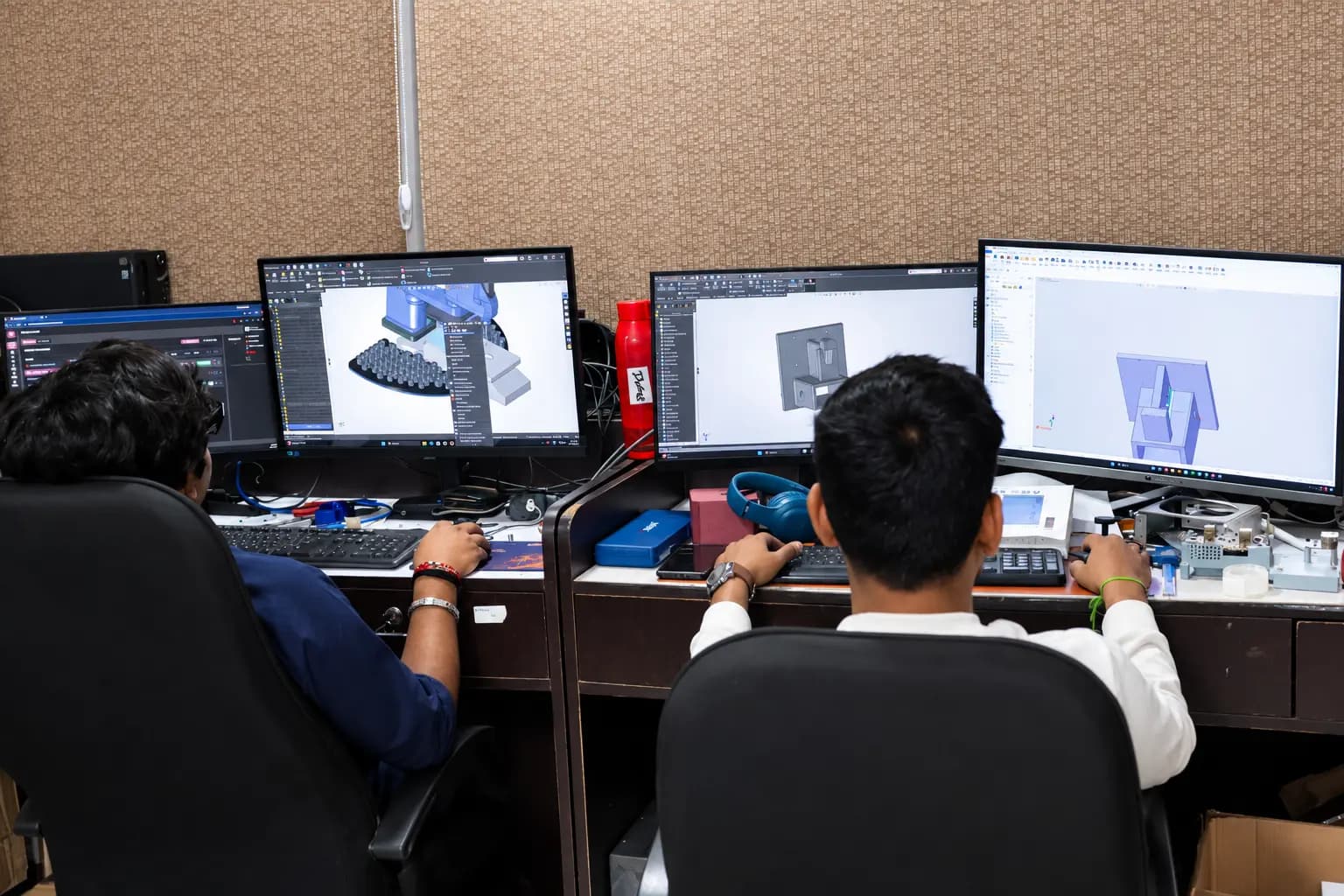 Mindron Lab engineers collaborating at multi-display engineering workstations on robotics and 3D modeling